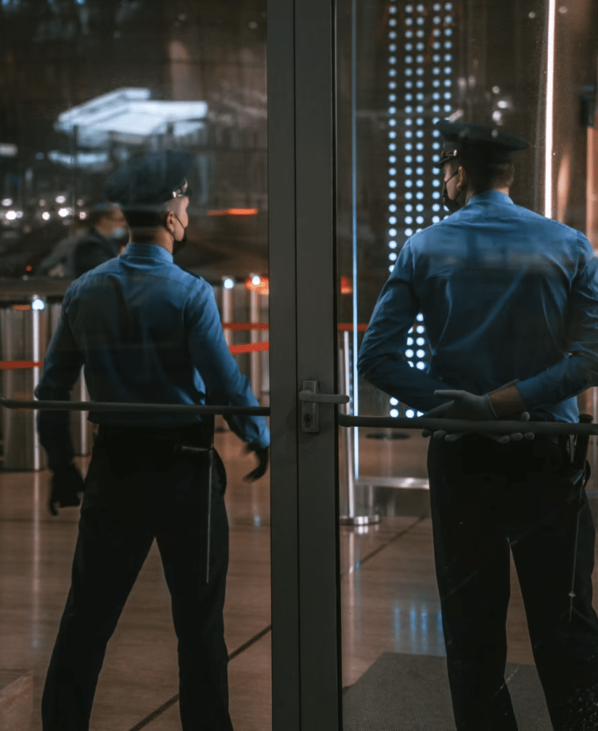 This photo shows two security guards standing near a building entrance.
