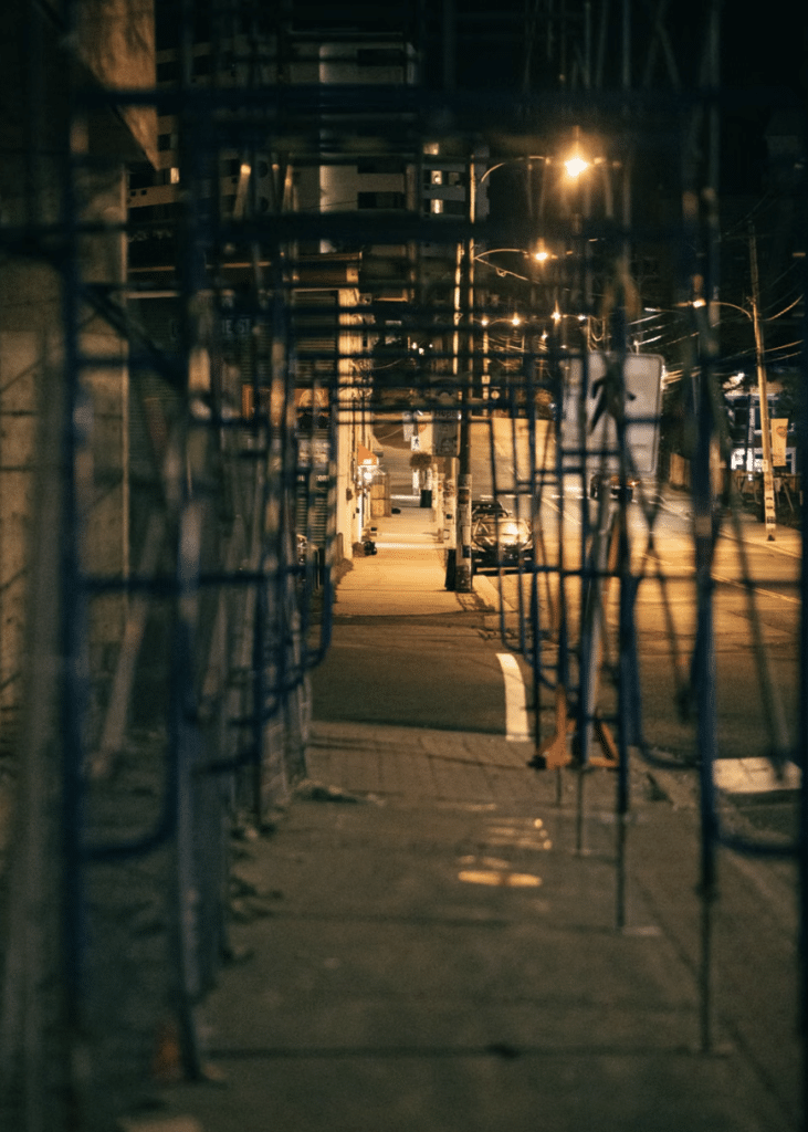 This photo shows a construction site at night with fencing and dim lighting.
